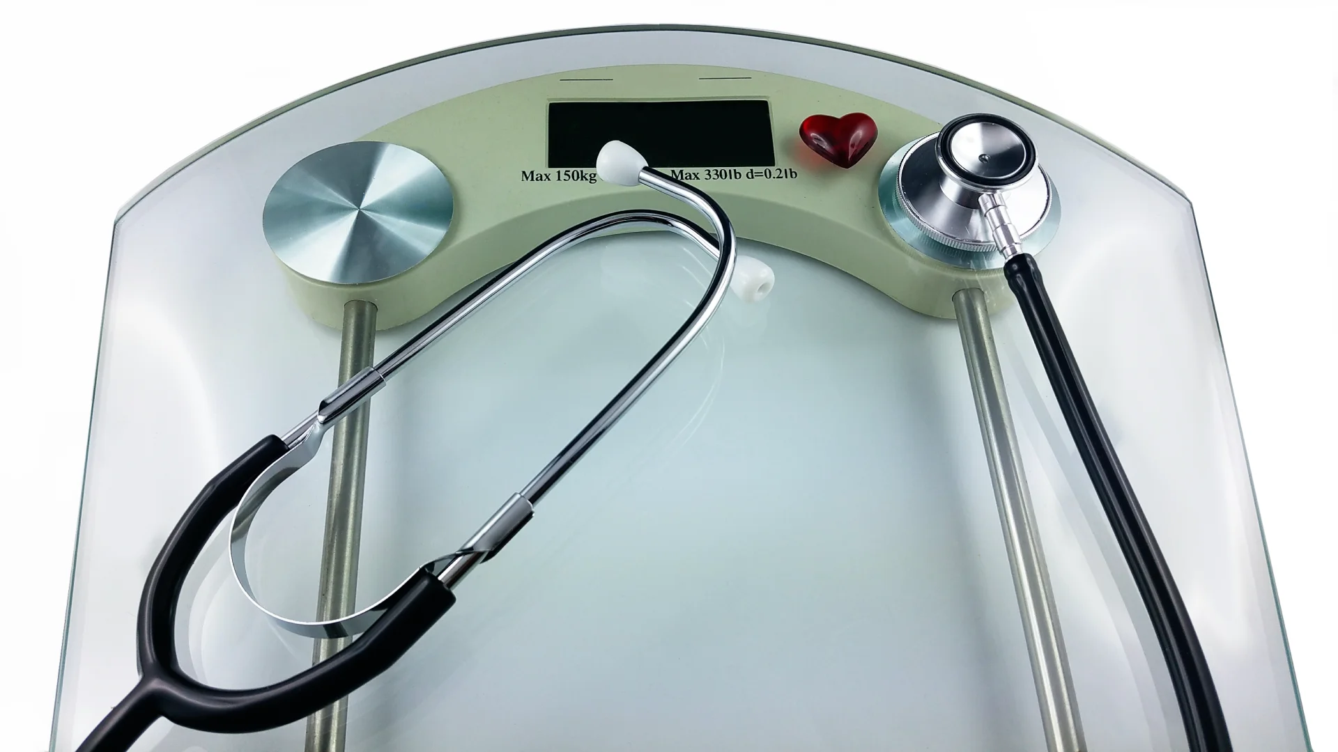 Waage mit Stethoskop und Herzsymbol darauf platziert, zeigt Verbindung von Gesundheit und Gewichtskontrolle.